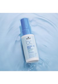 Sérum BC Bonacure Moisture Kick dans un flacon blanc avec une pompe bleue. Le texte sur l'étiquette inclut « Acide Hyaluronique 2 % », entouré d'un liquide bleu clair.