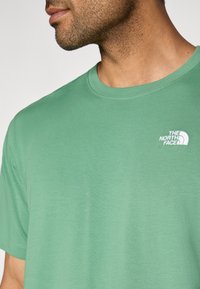 Ανοιχτό πράσινο βαμβακερό t-shirt με στρογγυλή λαιμόκοψη και μικρό λευκό λογότυπο στο αριστερό στήθος. Λεία υφή με κοντά μανίκια.