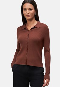 Gestreifter brauner Cardigan mit Kragen, durchgehenden Knöpfen und langen Ärmeln. Der Stoff wirkt strukturiert und sitzt eng am Körper.