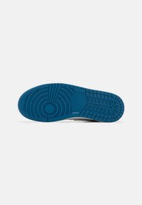 Semelle d'une chaussure Nike bleue avec des motifs circulaires et en grille, montrant le logo Nike au centre de la semelle.