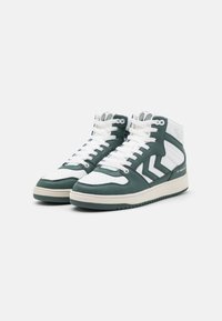 Wysokie sneakersy w białej i ciemnozielonej skórze z perforowanymi detalami, białymi sznurowadłami i beżową gumową podeszwą. Zawierają akcenty w kształcie chevronu.