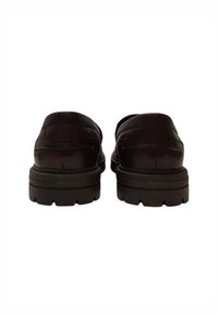 Scarpe in pelle nera con un design a profilo basso, punta rotonda e suola in gomma testurizzata con un modello di battistrada visibile.