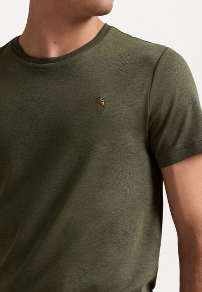Olivno zelena bombažna majica s kratkimi rokavi in krožnim izrezom, ki ima na levi strani prsnega koša manjši izšgan logotip konja. Ima kratke rokave in gladko teksturo.