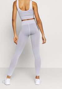 Ljusgrå ribbade sporttop och leggingsset, med en figurnära design och hög midja, kombinerat med vita träningsskor.