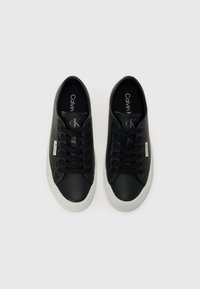 Black sneakers with smooth leather upper, lace-up design, and white rubber outsole. Features brand logo on tongue and side.