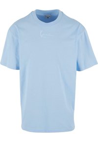 T-shirt en coton bleu clair avec un col rond et des manches courtes. Présente un logo blanc discret sur la poitrine. Design simple et classique.