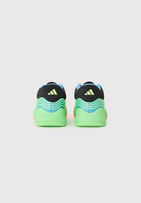 Chaussures de sport avec une tige noire et bleue, une semelle intermédiaire verte ondulée et des accents orange. Présente trois rayures noires à l'arrière.
