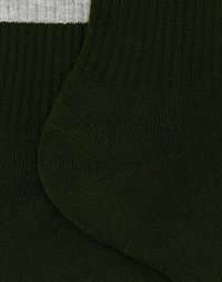Calze verdi a coste con una striscia orizzontale bianca nella parte superiore. La texture è liscia e il tessuto sembra elastico e morbido.