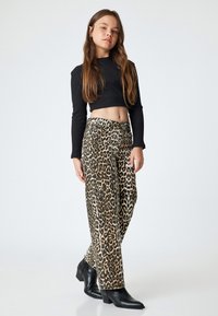 Top corto de manga larga de canalé negro combinado con pantalones anchos de estampado de leopardo, con una paleta de colores neutros y botines negros.