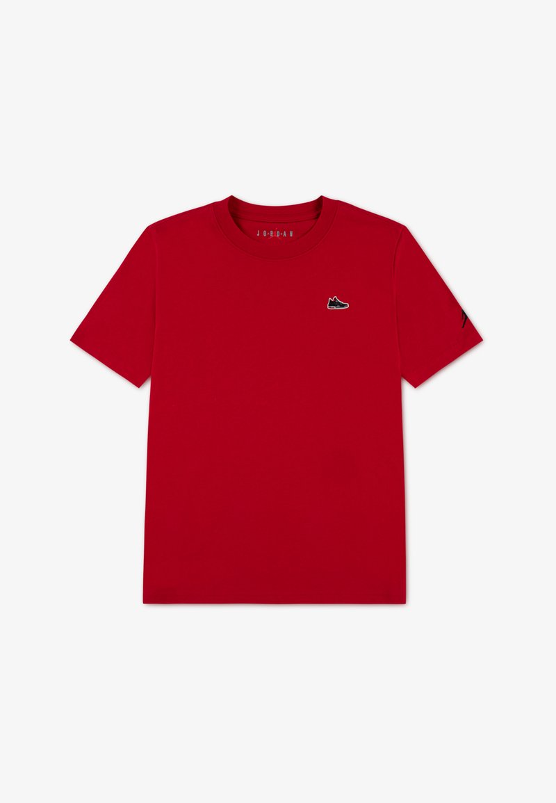T-shirt en coton rouge avec col rond, manches courtes et petit logo de basket noir sur la poitrine. Présente une texture lisse.