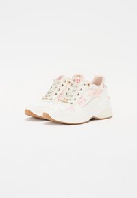 Valkoiset lenkkitossut, joissa vaaleanpunaiset kukkakoristeet, teksturoitu nauha ja kultaiset metalliosat. Paksu kumiulkopohja, jossa lievä korko.