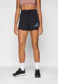 Calças de desporto pretas com cintura ajustável por cordão, apresentando um logótipo cinza da Adidas na lateral. Feitas de um material texturizado e respirável.