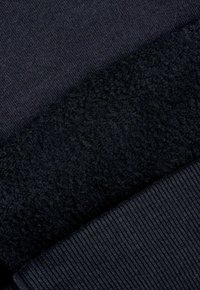 Ciemnoniebieskie próbki tkanin: jedna jest gładkim dzianiną, a druga to teksturowany polar z prążkowanym brzegiem na dole.