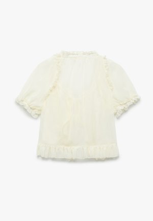 Blouse crème à manches courtes en tissu transparent. Présente des bords volants le long de l'encolure, des manches et de l'ourlet, créant un look délicat.
