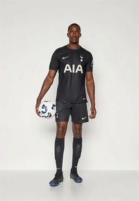 Sort fodboldudstyr med et struktureret mønster; har "AIA" logo i guld, klubemblem på brystet, samt shorts og knæhøje sokker.