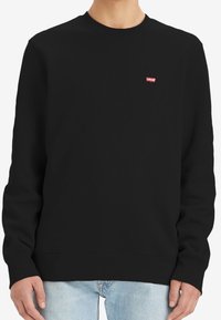 Sudadera negra con mangas largas, cuello redondo y puños de canalé. Cuenta con un pequeño logo rojo de Levi's en el pecho. Textura de tela suave.