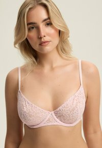 Koronkowy biustonosz braletka w delikatnym różowym kolorze, z subtelnymi wzorami kwiatowymi, regulowanymi ramiączkami i gładkim pasem dolnym dla wsparcia.