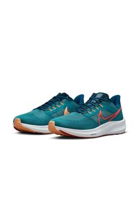 Tyrkysové sportovní boty s prodyšným síťovaným svrškem, světlehnědou gumovou podrážkou a červenými akcenty; zahrnují polstrovaný límec a systém šněrování.