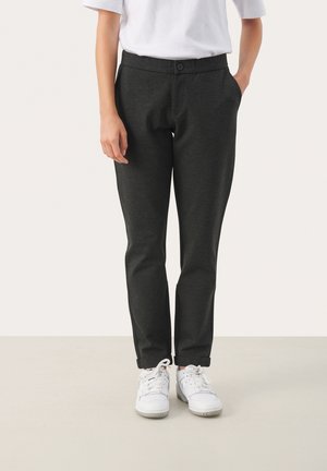 Donkergrijze tapered broek met een soepele textuur, voorzien van een knoopsluiting en zijzakken. Gepaard met witte sneakers.