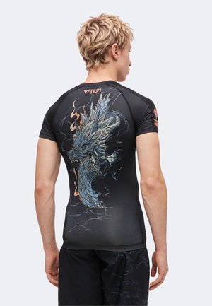 Homme portant un maillot de sport noir avec un graphisme détaillé de dragon bleu et le mot « VENUM » dans le dos, vu de dos.