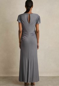 Hosszú szürke ruha rövid, redőzött ujjakkal, hátul kulcslyuk alakú kivágással és slim fit fazonnal, amely enyhén kiszélesedik az alján. Simább anyag textúrája.