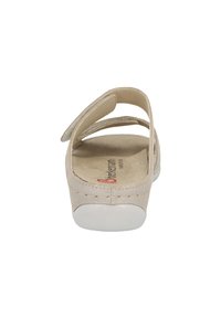 Beige sandal with a suede upper, open back, and adjustable straps. Soft insole, white rubber outsole, and subtle stitching details.