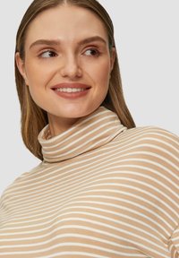 Beiger und cremefarbener gestreifter Rollkragenpullover mit weicher Textur, der über einen hohen Kragen und ein tailliertes Design verfügt. Minimalistischer Stil und gleichmäßiges Muster.