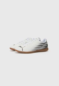 Hvite sporty sko med svarte detaljer, med et strømlinjeformet design, teksturert gummisåle og signaturlogo på siden.