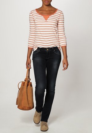 Langarm gestreept shirt in wit en oranje, donkerblauwe spijkerbroek, beige schoenen en een tan suède tas. Casual outfit met een ontspannen pasvorm.