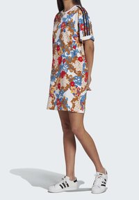 Korte mouwen bloemdress met blauwe, rode en gouden patronen op een witte achtergrond; heeft zwarte gestreepte accenten op de mouwen.