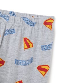 Grijze katoenen shorts met een herhalend patroon van gele en rode superheldenlogo's en blauwe tekst met de tekst "SUPERMAN." Elastische tailleband.
