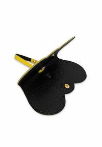 Accessoire en cuir noir avec des bords festonnés, fermeture à bouton pression dorée et une sangle jaune contrastante. Surface texturée avec un fini légèrement brillant.