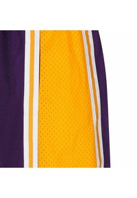 Paarse en gele sportshorts van ademend mesh-materiaal, met een witte en oranje streep langs de zijkanten. Textuur op het oppervlak en sportief ontwerp.