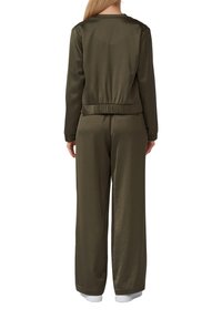 Completo a due pezzi verde oliva composto da una giacca aderente e pantaloni a gamba larga, realizzato in tessuto liscio con polsini e vita elasticizzati. Senza fantasie.