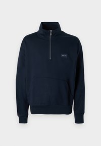 Πουλόβερ sweatshirt σε ναυτικό μπλε χρώμα, κατασκευασμένο από βαμβάκι, με ψηλό γιακά, μισό φερμουάρ, μπροστινή τσέπη και ριμπ μανσέτες και τελείωμα. Μι κρή λεπτομέρεια με λογότυπο.