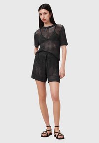 Sort strikket mesh top med korte ærmer og matchende shorts med elastisk talje og snor. Båret med sorte stroppesandaler.