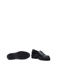 Zapatos loafers negros de piel lisa, con una suela de goma gruesa y detalles de tachuelas en la parte superior. Suela plana y texturizada.