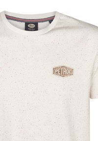 Kortærmet t-shirt i lys creme med en spraglet tekstur. Har et brunt logo-patch på brystet og en kontrasterende krave.