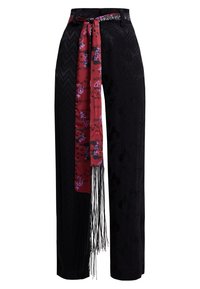 Pantalon noir à jambes larges avec un motif texturé, doté d'un foulard rouge à motifs avec des franges noué à la taille.