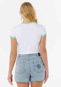 T-shirt blanc coupé avec col et manches côtelés vert menthe, associé à un short en denim bleu clair avec broderie sur la poche arrière.