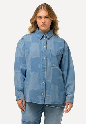 Světle modrá džínová košile s patchworkovým designem, zapínání na knoflíky, klasický límec a jedna kapsa na hrudi. Vyrobena z měkké, texturované tkaniny.