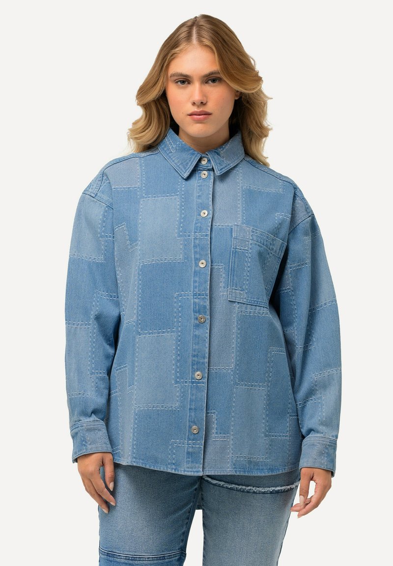 Lichtblauwe spijkerblouse met een patchworkontwerp, knoopsluiting aan de voorkant, klassieke kraag en een enkele borstzak. Gemaakt van zachte, gestructureerde stof.