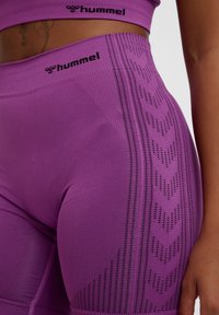 Leggings taille haute violets présentant un motif texturé avec des détails découpés, fabriqués en matériau extensible avec une finition lisse.