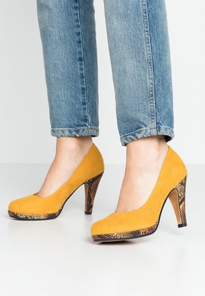 Zapatos de tacón alto de ante amarillo con un patrón texturizado de piel de serpiente en el tacón. Presentan una puntera redonda y un tacón stiletto delgado de madera.