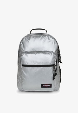Silver nylon backpack with a main compartment, front zip pocket, and mesh side pocket. Features black zipper and logo patch.