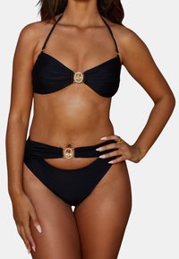 Zwart bikini-set met een bandeau-top voorzien van een centrale detail met strassaccent. De broekjes hebben een hoge snit en een bijpassende versiering.