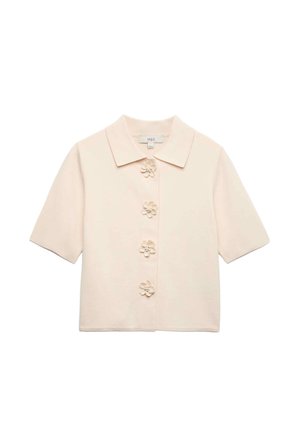 Blouse crème à manches courtes avec un col pointu et quatre boutons décoratifs en forme de fleur sur le devant.