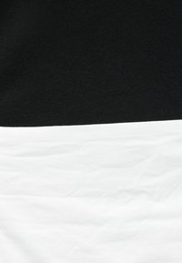 Μαύρο ύφασμα στρωμένο πάνω από τσαλακωμένο λευκό ύφασμα, που δείχνει τις διαφορές υφής μεταξύ λείο και ζαρωμένο επιφάνειας.