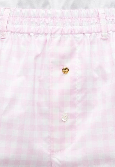 Shorts à motif vichy rose clair et blanc avec ceinture élastique et deux boutons à l'avant, un doré et un blanc.