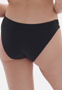 Svart bikiniunderdel med en slät textur och låg skärning. Har en scalloped midjebanddetalj och minimal sömnad i kanterna.